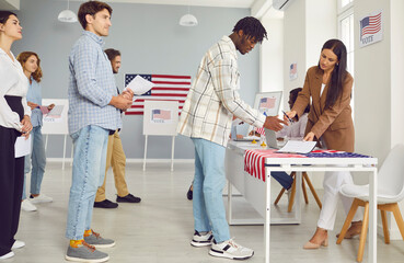 Voting in elections. African American male voter signs during registration at polling place on...