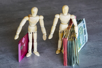 Two wooden human figures symbolize the concept of using cash or payment cards, cash or card choice