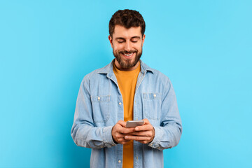 Happy young man browsing an app on his smartphone, studio