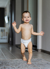 Small child is walking in diapers in the room