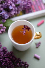 Obraz na płótnie Canvas spring art still life: tea in legant cap with lilac petals, fresh lilac and soft pastel crayons