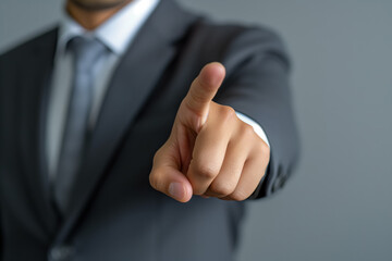 A male businessman in a business suit points his finger in the direction on a grey background