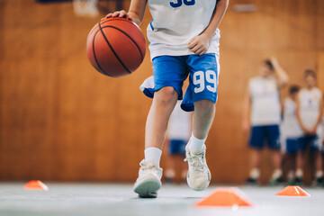 Naklejka premium Cropped picture of a junior athlete dribbling basketball on court.