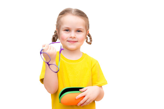 A cute girl in a bright yellow T-shirt holds glasses in her hands. White background.