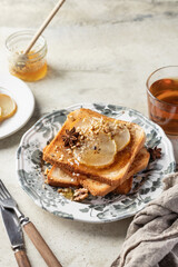 Sweet toast with cream cheese, caramelized pear, nuts and honey with cup of tea for breakfast on textured background