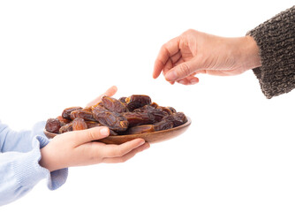 Unrecognizable caucasian child holding full wooden plate of date fruits. Woman hand taking one. Side view isolated white background. Copy space. Islam hold month Ramadan special snack concept image.