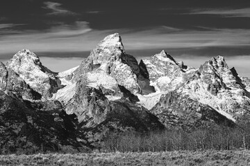 Classic black and white snow-covered Grand Teton Mountain Range and winter meadow landscape...