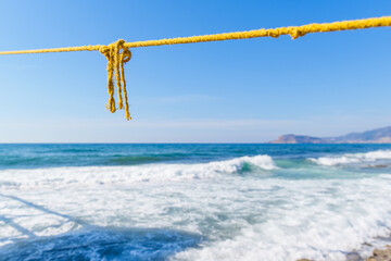 Obraz premium Rope String knot Hanging on a Wooden Boardwalk Bay at a Sandy Beach Infront of the Blue Sea and Sky