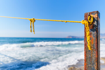 Rope String knot Hanging on a Wooden Boardwalk Bay at a Sandy Beach Infront of the Blue Sea and Sky