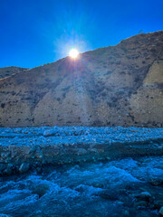 A Sunburst from over a Cliff next to a River