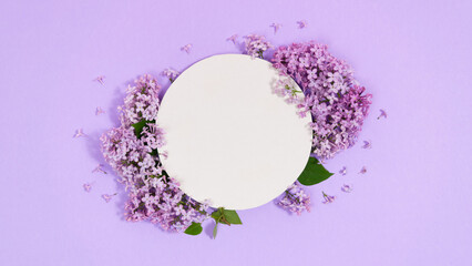 Natural branches and flowers of lilac near round white piece of paper. Сoming of spring. Lilac background.