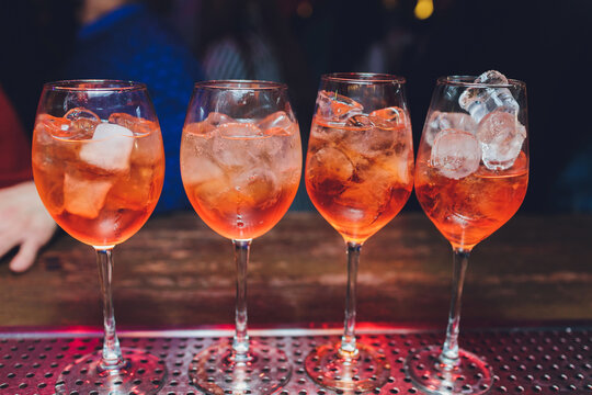 Campari tonic alcoholic cocktail with red bitter, tonic, lime and ice. Old wooden table background, bar tools, selective focus. All names refer to cocktails, not trademarks.