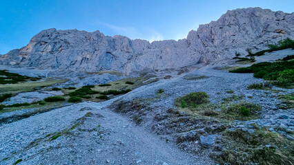 Panoramic view of majestic mountain cliff Schartenspitze in untamed Hochschwab mountain region, Styria, Austria. Scenic hiking trail in shadows in remote Austrian Alps. Wanderlust in alpine summer