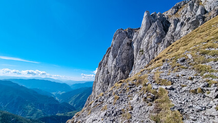 Panoramic view of majestic mountain cliff Schartenspitze in untamed Hochschwab mountain region, Styria, Austria. Scenic hiking trail in shadows in remote Austrian Alps. Wanderlust in alpine summer