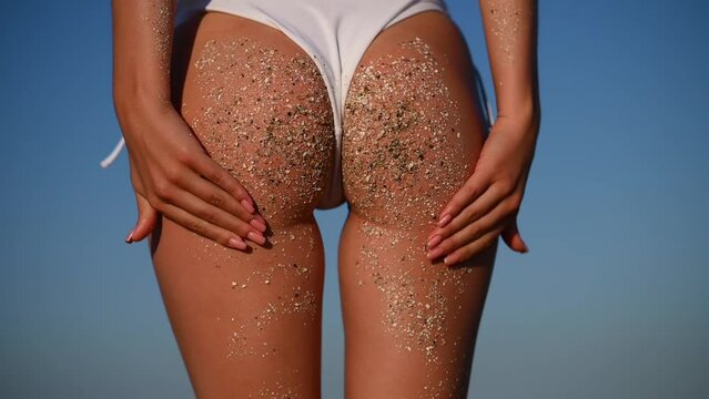 close-up of a girl's butt in a white swimsuit. Sexy girl's butt on the beach in the sand