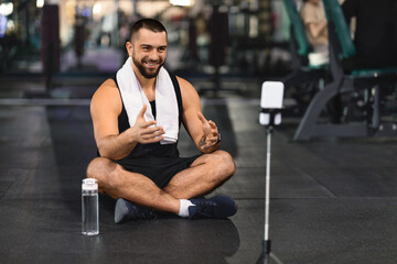 Fototapeta na wymiar Blogging Concept. Smiling Muscular Man Recording Video Content At Gym
