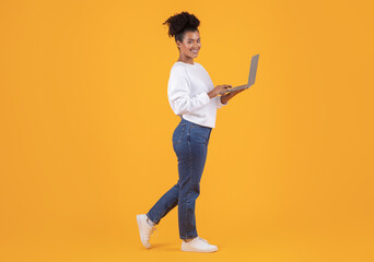 Smiling Black Woman With Laptop Computer In Hands Standing On Yellow Background