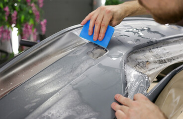 Close up of paint protection film installation on front bumper of modern luxury car. PPF is...