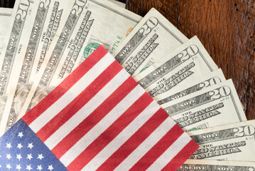United States currency and flag.  Twenty-dollar bills fanned out on a wooden background.