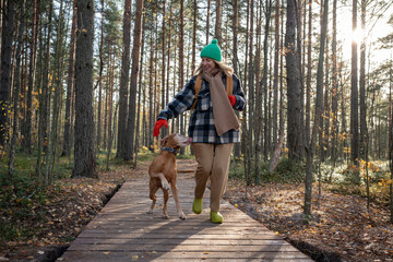 Cheerful loving middle age dog owner spends free time in pine forest hiking, walking with fur...