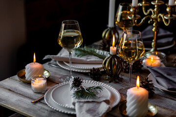 Rustic Scandinavian style zero waste eco-friendly dinner table decor for Christmas or new year family celebration. Wooden table, natural elements like pine cones, fir tree branches, candles