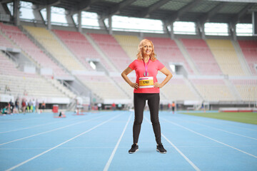 Naklejka premium Full length portrait of a mature female runner standing on a running track