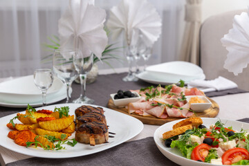 Grilled meat on a skewer, greec salad and meat platter on a served for dinner table.