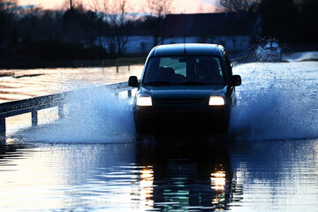 Samochody na zalanej drodze przez wodę z rzeki. Powódź. 