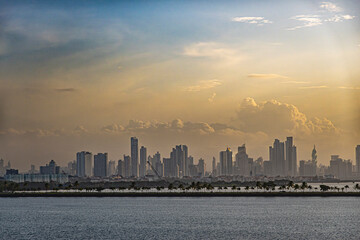 Fototapeta premium Panama Canal, Panama - July 24, 2023: long Amador Causeway in front of city skyline at entrance to canal, Pacific side under yellow morning sunrise cloudscape. 