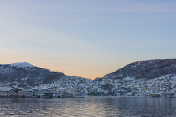 South part of bay of Bergen in early morning of winter. Sun slowly rising behind the mountains revealing suburbs of Laksevåg and Damsgard