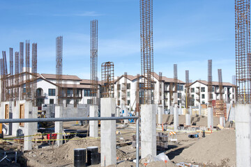 Pillars being constructed for new housing with recently finished apartment complexes in the background. California housing market
