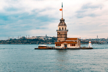 Fototapeta premium Maiden's Tower (Kız Kulesi), the famous symbol of Turkey, on the Bosphorus. View of the Bosphorus and the Maiden's Tower with a cloudy blue sky on a sunny day.