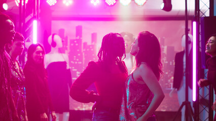 Young adults dancing on cool beats, men and women preparing for dance battle at nightclub. Group of people having fun showing off modern funky moves and skills, enjoying party. Tripod shot.