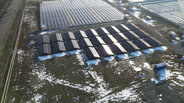 Aerial footage captures the majestic expanse of a solar farm, showcasing a photovoltaic power station in action during the cold season. Drone flyover of this innovative solar park on a winter  day.
