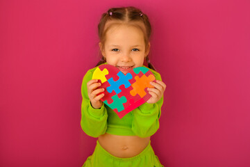 A girl with a heart-shaped postcard decorated with colored puzzles, made in support of autistic...