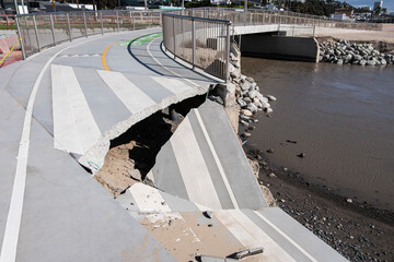 Collapsed concrete blocking beach bike path bridge.  Damage is from winter storm in the Pacific Palisades neighborhood of Los Angeles, California. - obrazy, fototapety, plakaty