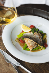 Appetizing fried piece of fish fillet on a large white plate. Restaurant, banquet, buffet.