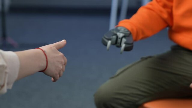 A female hand shakes a robotic hand. A female hand shakes a robotic hand. A man with a prosthetic arm