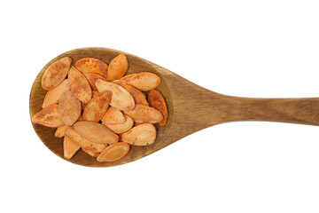 Pile roasted pumpkin seeds with salt in wooden spoon isolated on white