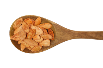 Pile roasted pumpkin seeds with salt in wooden spoon isolated on white