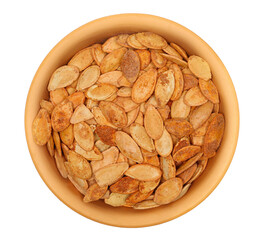 Pile roasted pumpkin seeds with salt in clay pot isolated on white