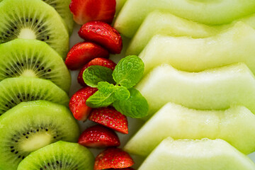mixed fruit plate containing melon, strawberries, oranges and kiwi.