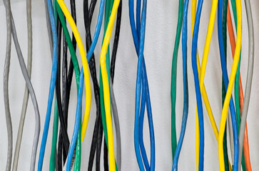 Colorful CAT5 Twisted pair cables electrical cords hanging on wall computer networks equipment.