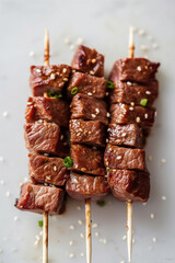 Wagyu meat pieces skewered on bamboo skewers against the light grey background