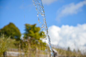 The stream of fresh and clean drinking water captured in detail, with sunlight reflecting off the...