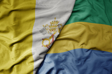 big waving national colorful flag of gabon and national flag of vatican city.