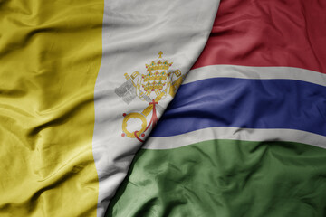 Fototapeta premium big waving national colorful flag of gambia and national flag of vatican city.