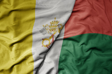 big waving national colorful flag of madagascar and national flag of vatican city.