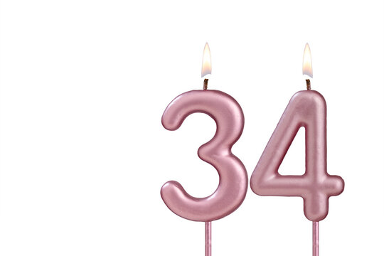 Candle number 34 - Lit birthday candle on white background