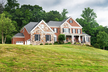 Brick country house with a large lawn and woods in the backyard.